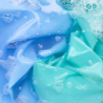 Blue and green fabric submerged in soapy water.