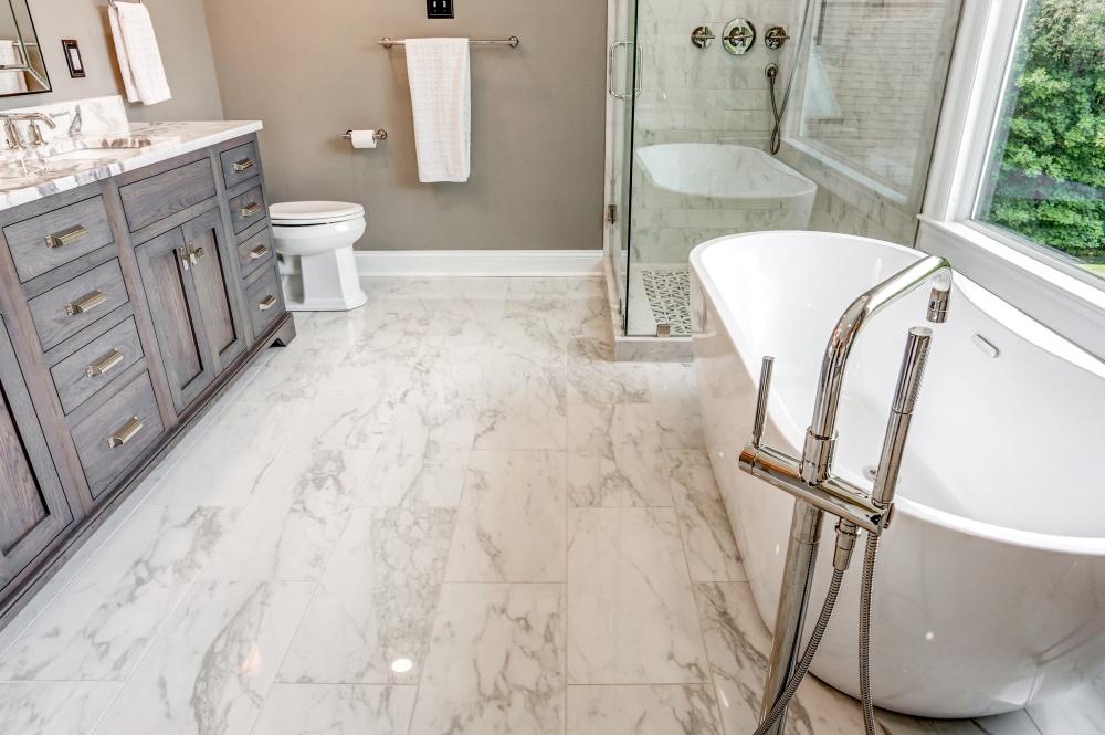 bathroom with large soaking tub, glass shower, sink, and toilet