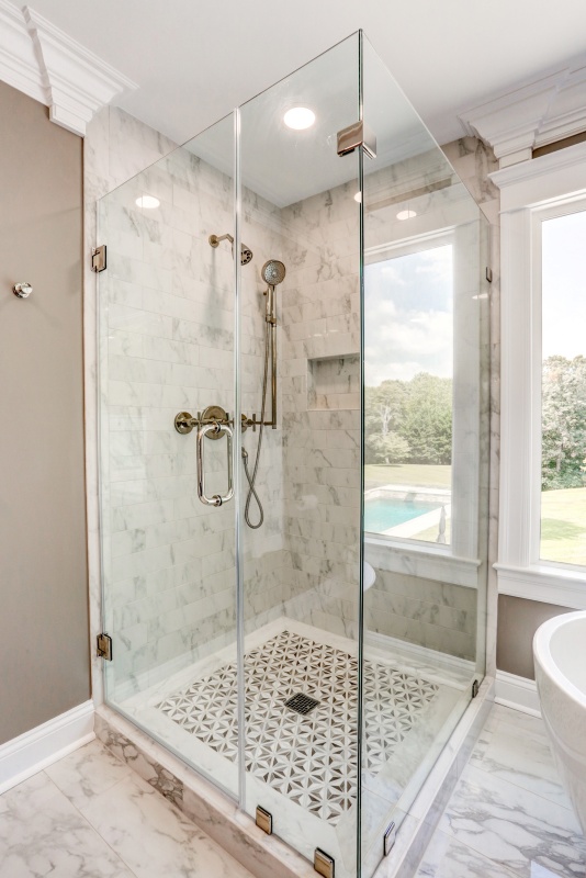 elegant glass shower with marble walls and intricate tile flooring