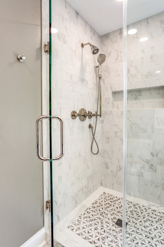 marble shower with beautiful tile flooring and recessed wall nook for shampoo and soap