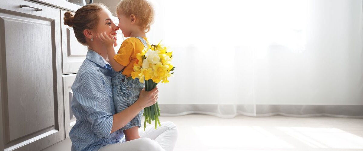 mother hugging child while holding daffodils